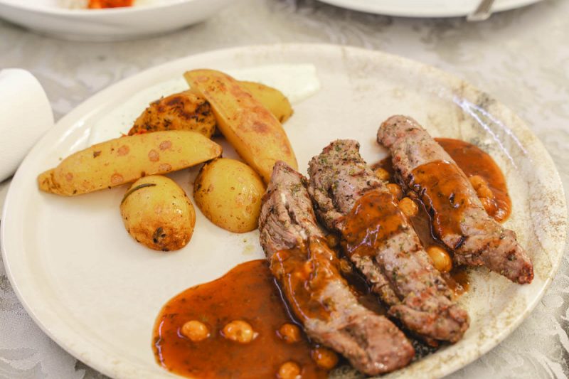 Gegrilltes Fleisch mit roter Soße und Kartoffelecken