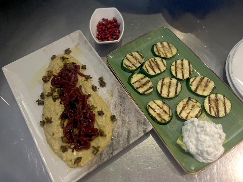 Gegrillte Zucchinischeiben auf einem grünen Teller mit Zaziki